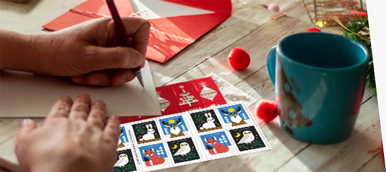 A person addressing a letter with 一流的邮件 Forever® holiday stamps on the table.